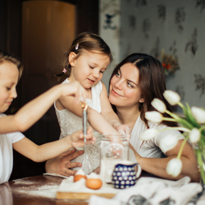 woman with her daughter and son at a table baking